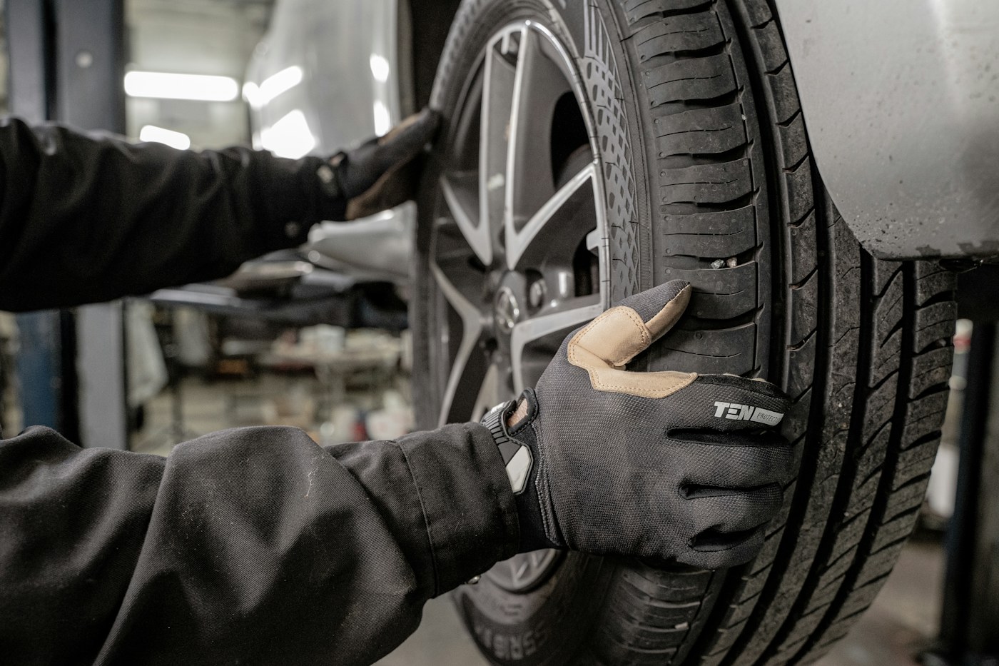 Gloved hands handling a vehicle tyre and wheel